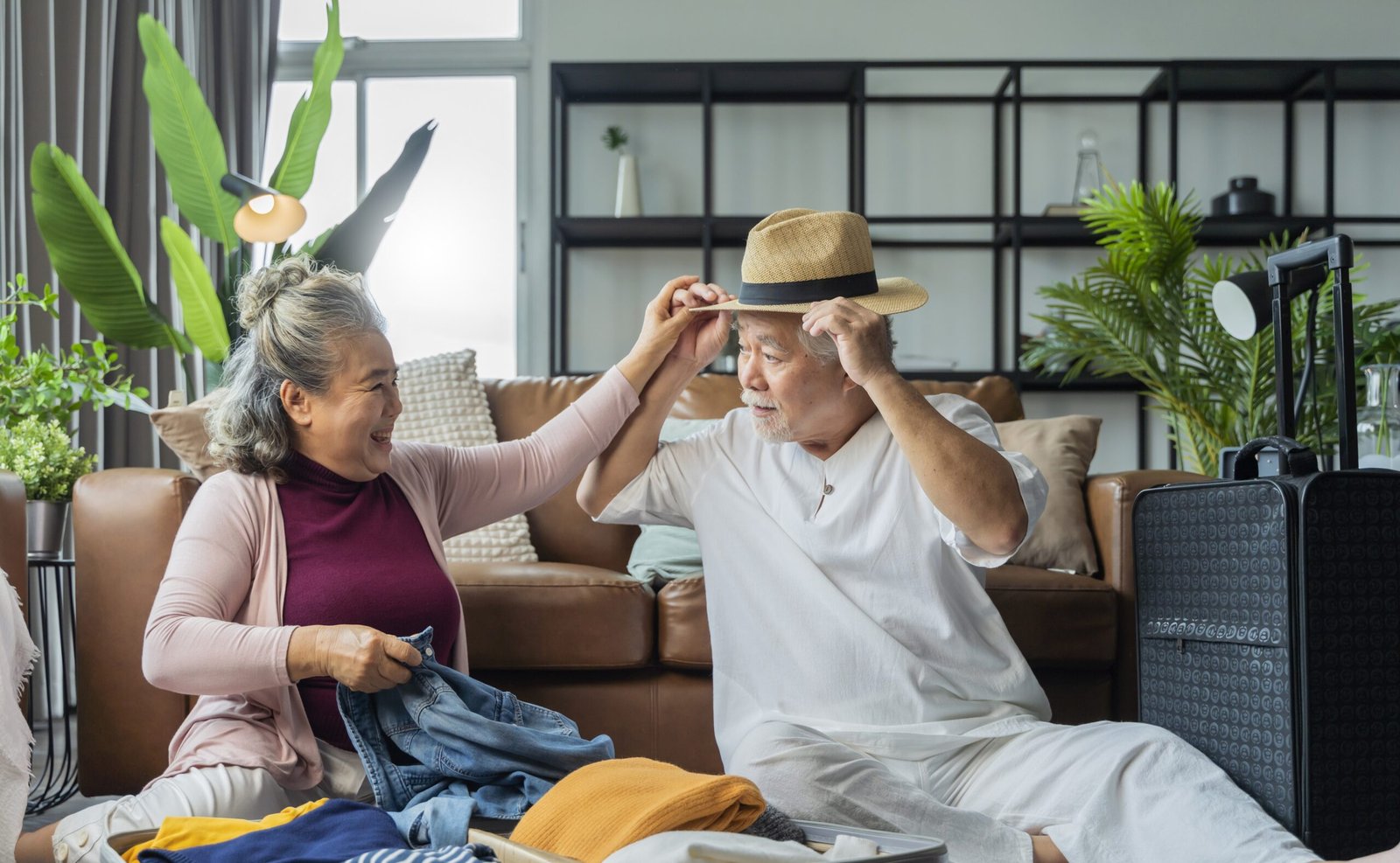 old asian senior couple packing cloth and stuff for a trip together,happiness asian old age retired mature adult enjoy arrange cloth together on floor at living room at home interior background