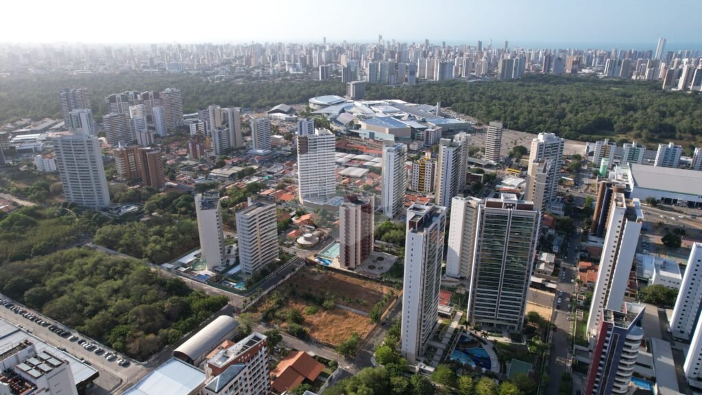 Imagem aérea do bairro Guaraparapes, em Fortaleza, no Ceará. Entre os prédios que aparecem na fotografia, é possível ver muita área verde e um horizonte de outros prédios. Também é possível perceber que é um bairro em desenvolvimento.